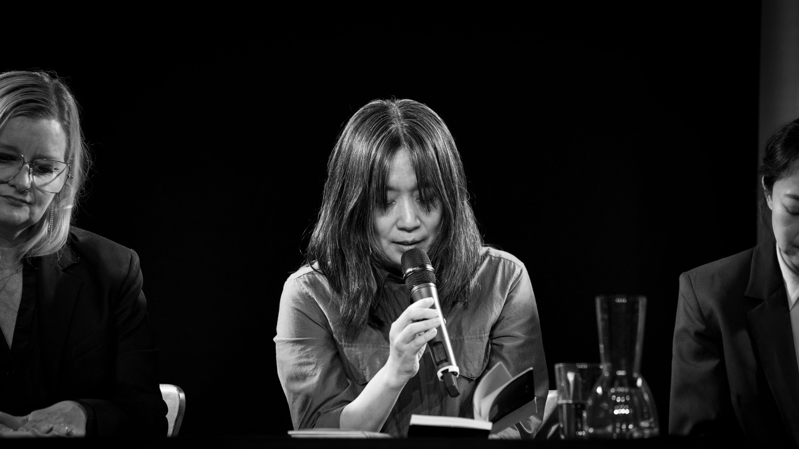 Die südkoreanische Literatur-Nobelpreisträgerin Han Kang sitzt auf einer Bühne und liest aus ihrem neuen Buch "Der goldene Faden".