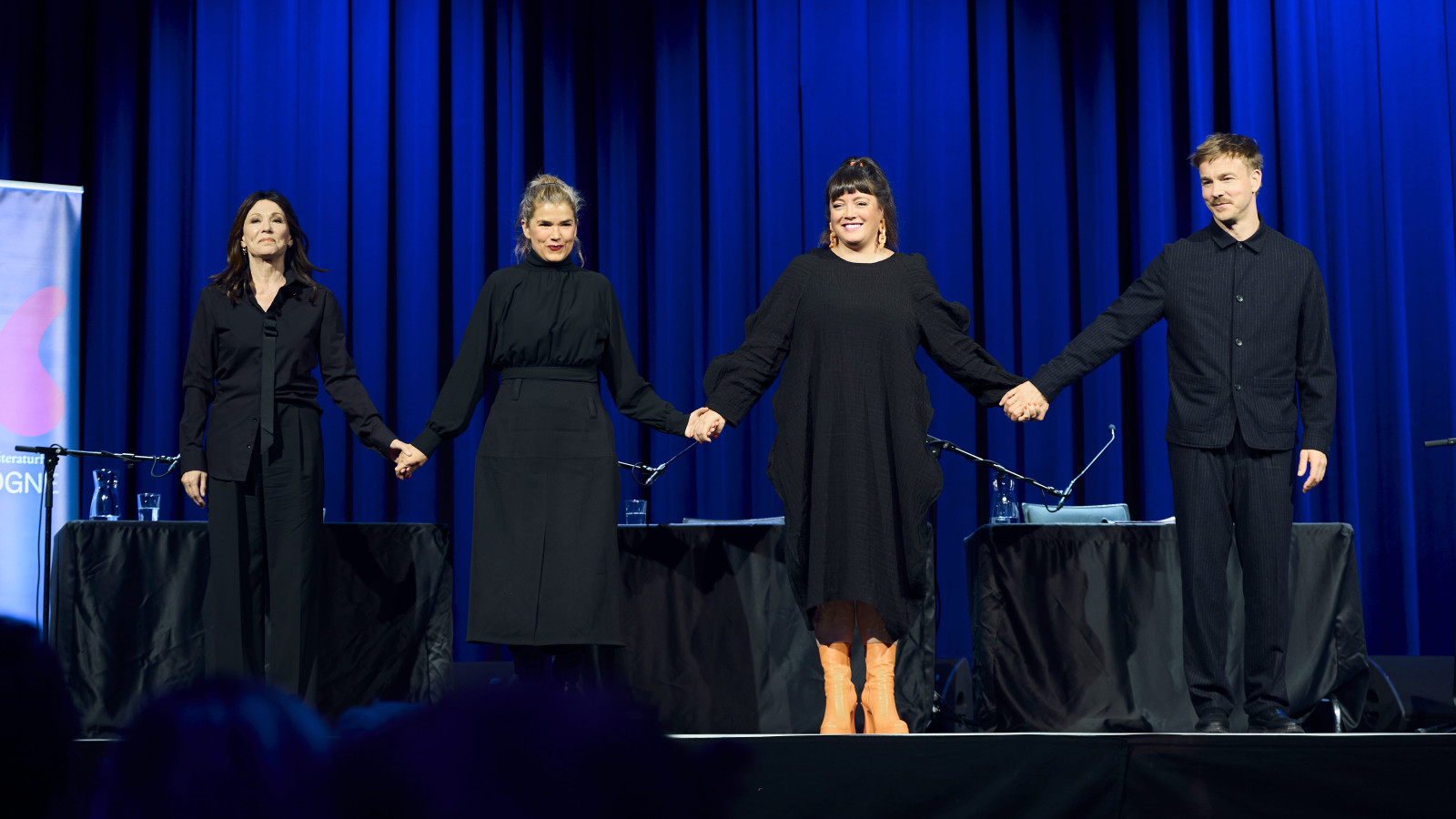 04.10: Diaries of Note. Iris Berben, Anke Engelke, Marie-Kristine Knop und Albrecht Schuch stehen auf einer Bühne, fassen sich an den Händen und lächeln Richtung Publikum.